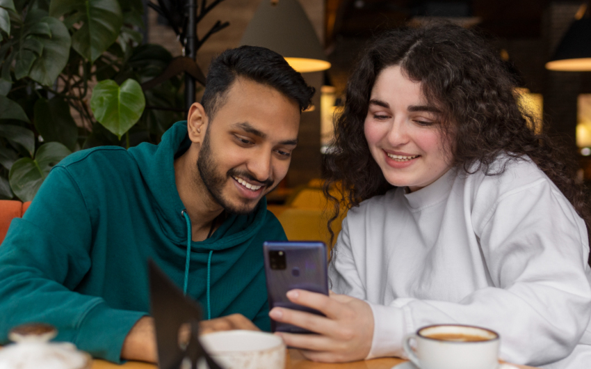 Imagen de dos personas observando un celular.